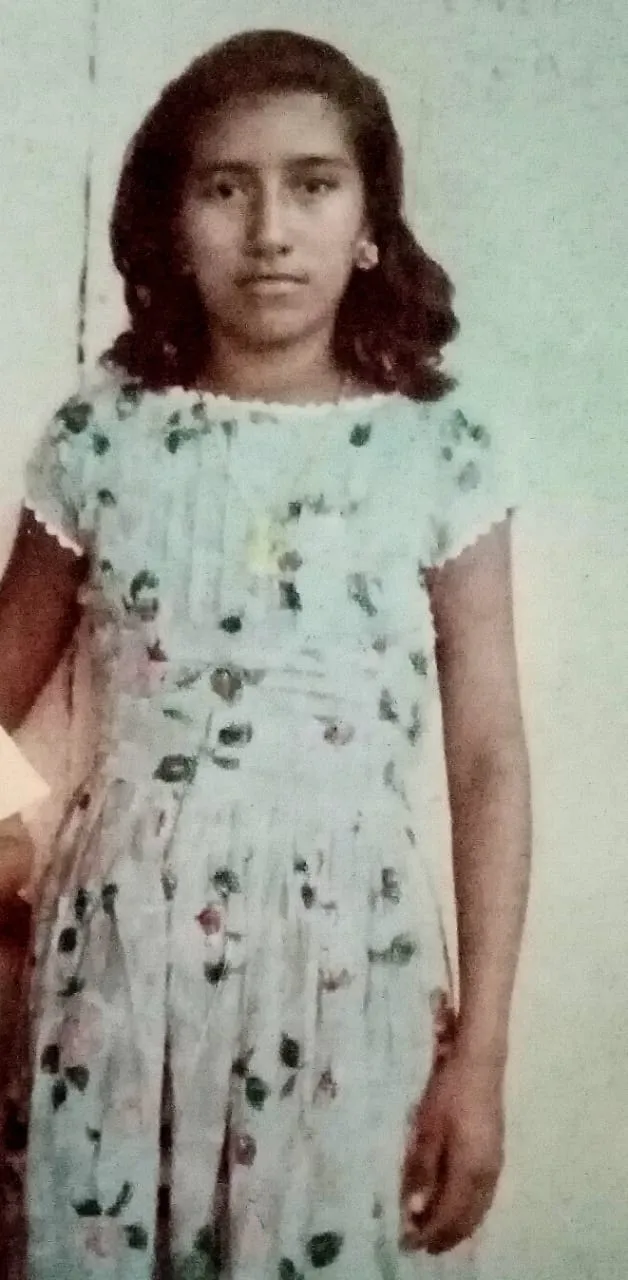 A girl in a floral dress, standing for a portrait